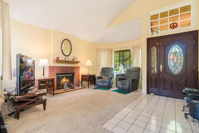 a living room with furniture a fireplace and a flat tv screen next to a window