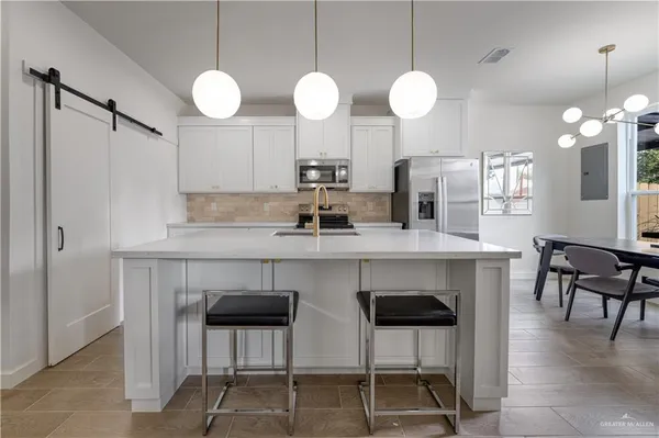 a kitchen with stainless steel appliances a dining table chairs and a refrigerator