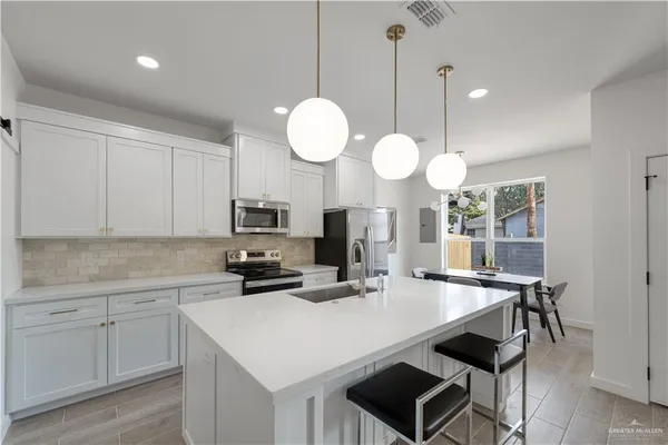 a kitchen with a dining table cabinets and stainless steel appliances