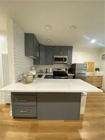 a kitchen with stainless steel appliances a sink a stove a microwave a sink a refrigerator and cabinets