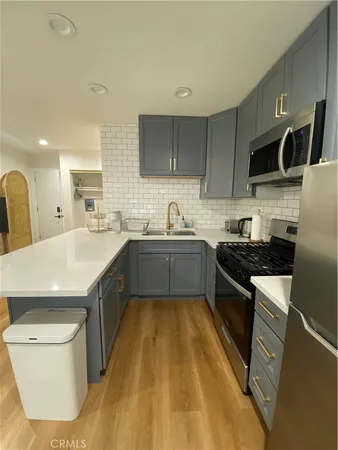 a kitchen with stainless steel appliances a sink a stove a microwave a sink a refrigerator and cabinets