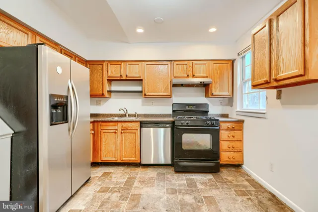 a kitchen with stainless steel appliances granite countertop a stove a sink and a refrigerator