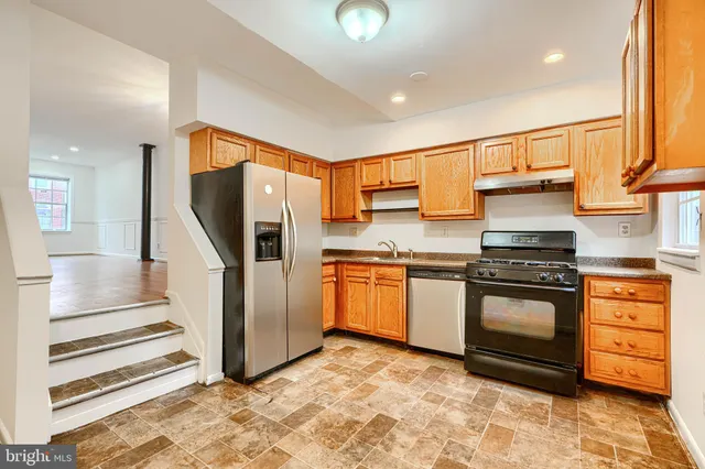 a kitchen with stainless steel appliances granite countertop a stove a sink and a refrigerator