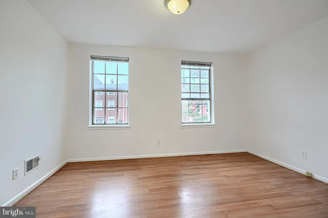 an empty room with wooden floor and windows