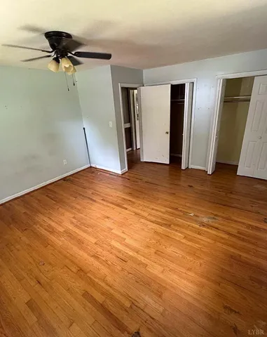 a view of an empty room with a ceiling fan and wooden floor