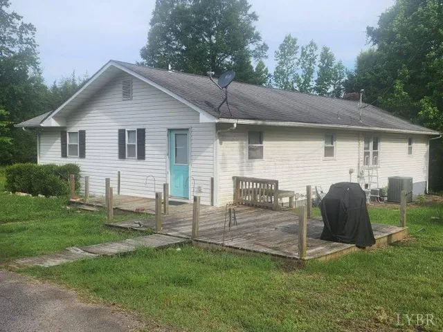 a view of a wooden house with a yard and large trees