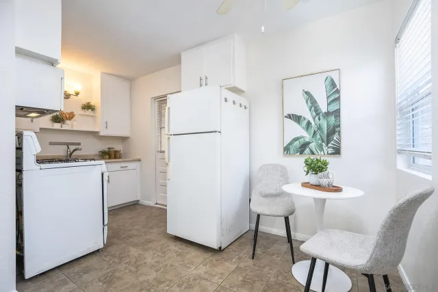 a kitchen with a refrigerator white cabinets and wooden floor