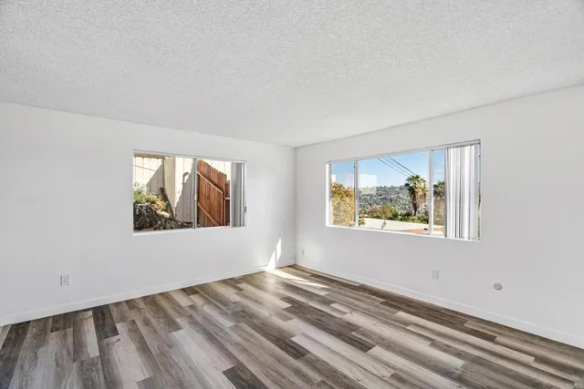 a view of empty room with window and wooden floor
