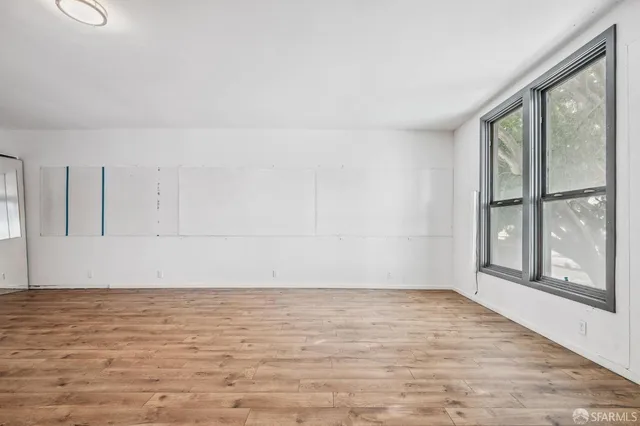 a view of an empty room with wooden floor and a window
