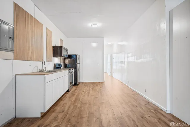 a large white kitchen with wooden floor and white cabinets