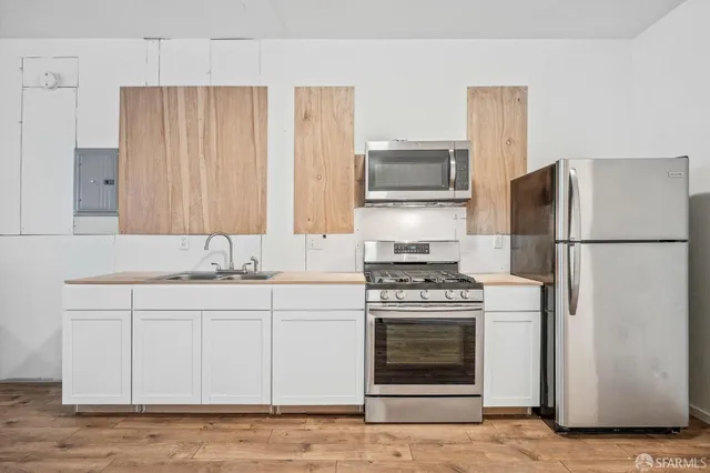 a kitchen with cabinets stainless steel appliances and wooden floor