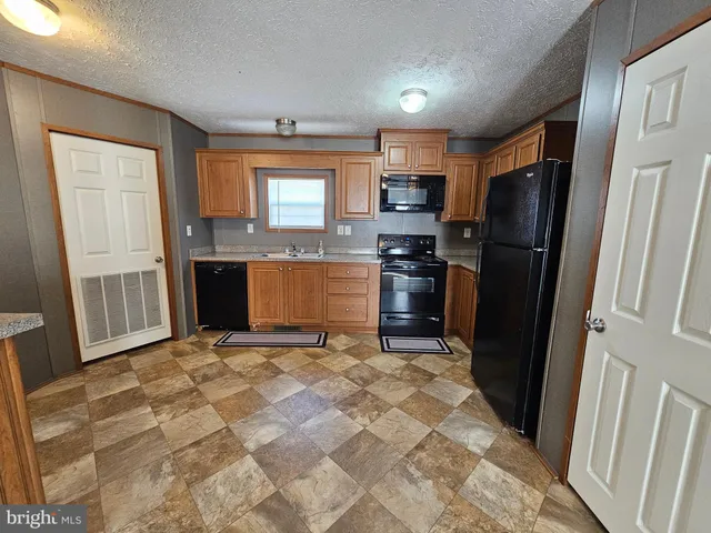 a kitchen with granite countertop a refrigerator stove and sink