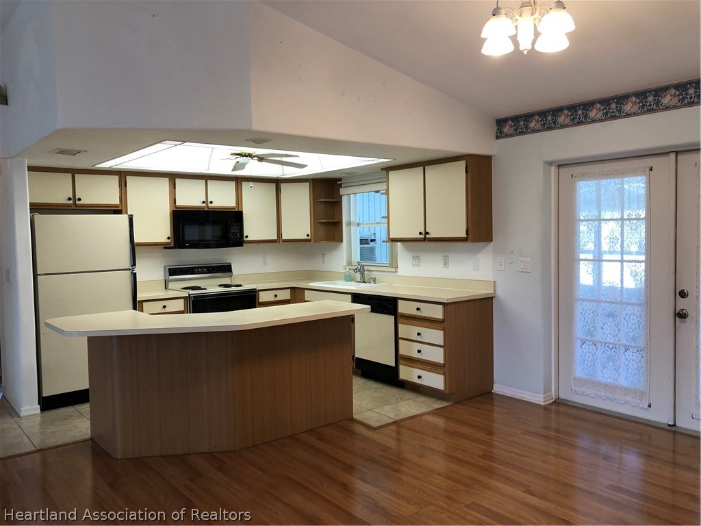 4440 Mandarin Road Sebring, FL 33875 - Photo 6 of 17 a kitchen with stainless steel appliances kitchen island granite countertop a stove a sink and a microwave