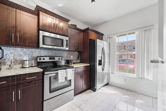 a kitchen with stainless steel appliances granite countertop a refrigerator and a stove top oven