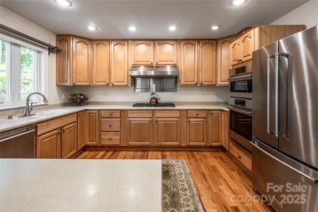 a kitchen with kitchen island granite countertop a sink stainless steel appliances cabinets and a counter top space