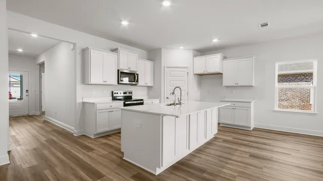 a large kitchen with stainless steel appliances a large counter top a sink dishwasher and a refrigerator