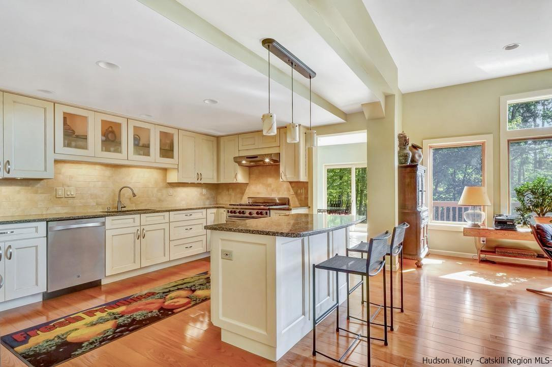 71 Carly Road Woodstock, NY 12498 - Photo 7 of 34 a kitchen with stainless steel appliances granite countertop a stove top oven a sink a dining table and chairs with wooden floor
