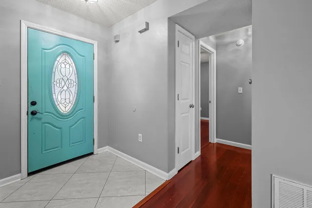 an empty room with wooden floor fan and windows
