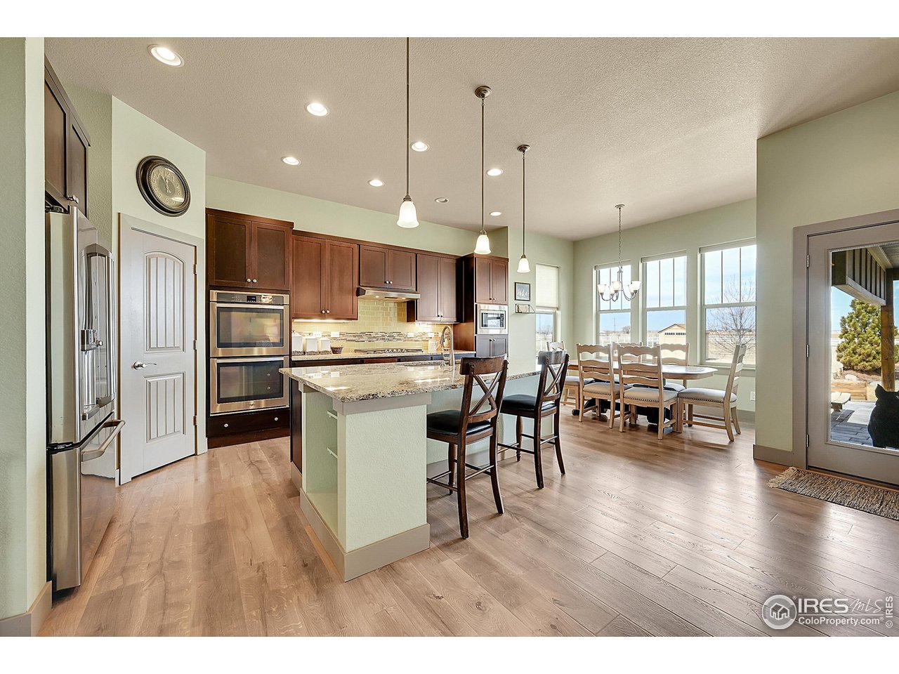 40775 Jade Drive Ault, CO 80610 - Photo 8 of 40 a kitchen with a refrigerator a sink dishwasher a dining table and chairs with wooden floor