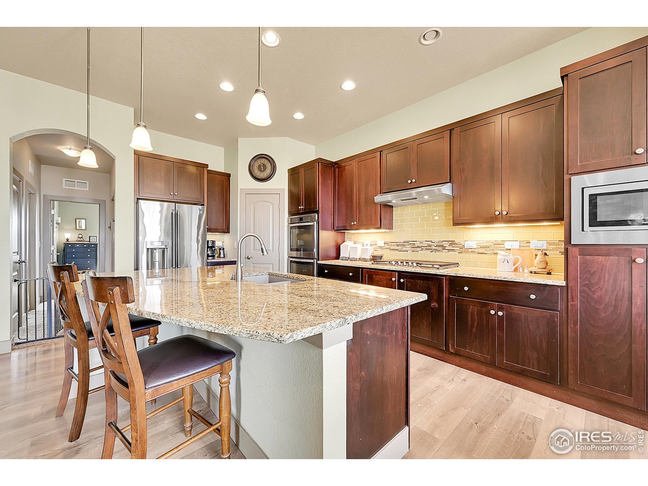 40775 Jade Drive Ault, CO 80610 - Photo 9 of 40 a kitchen with stainless steel appliances kitchen island granite countertop a table chairs sink and cabinets