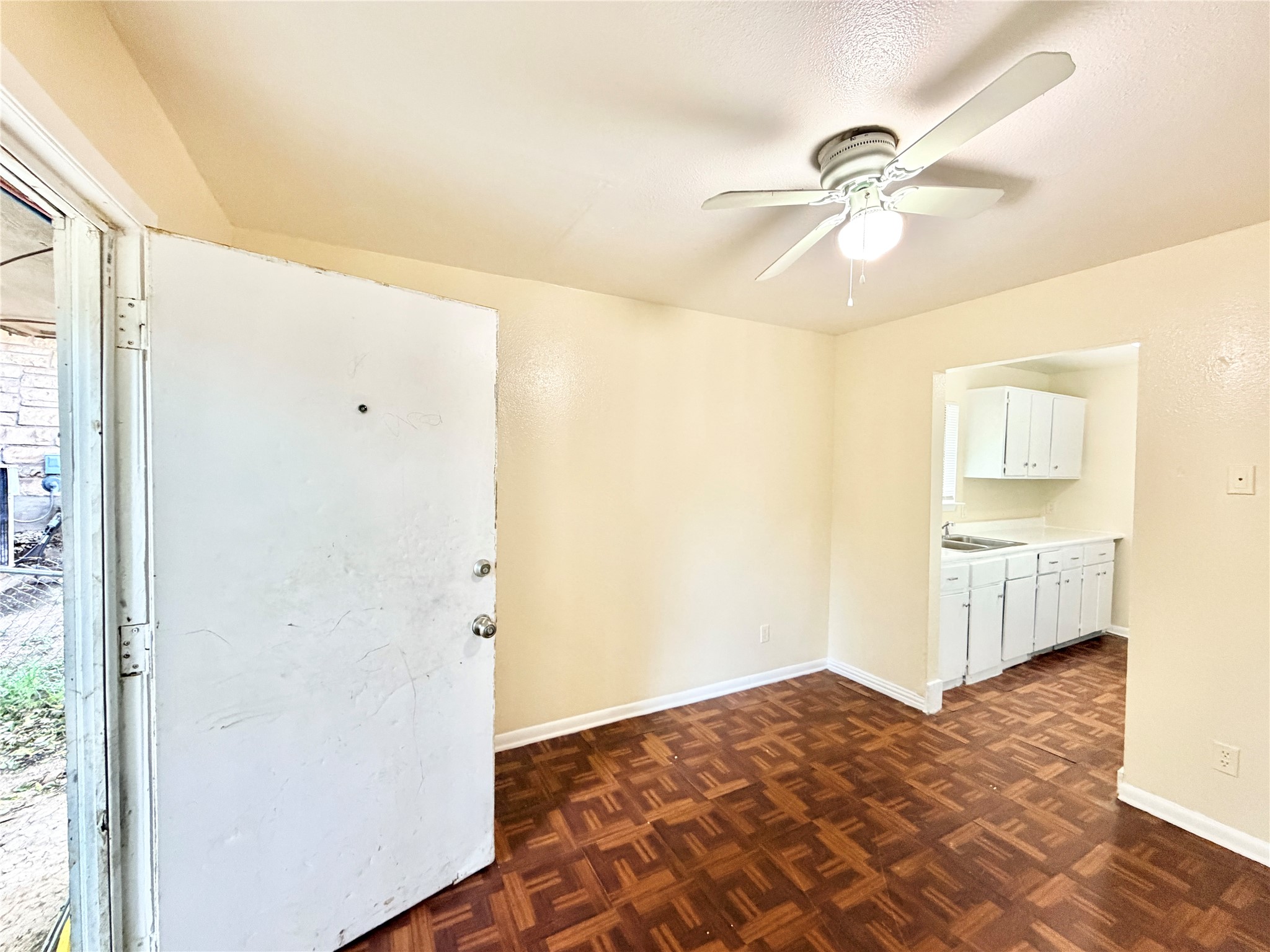6257 Manor Road, Unit B Austin, TX 78723 - Photo 14 of 38 Entry area featuring wood-finish flooring, a ceiling fan with integrated lighting, and direct access to a kitchen alcove with white cabinetry and a sink