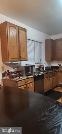 a kitchen with granite countertop a stove a sink dishwasher and a microwave oven with wooden cabinets