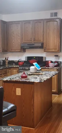 a view of kitchen with granite countertop wooden cabinets