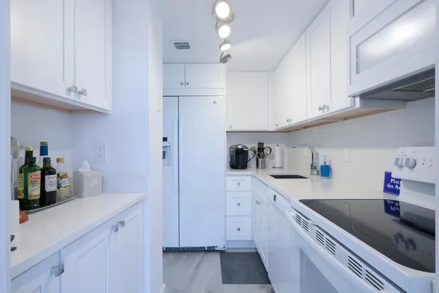 a kitchen with granite countertop white cabinets and white appliances
