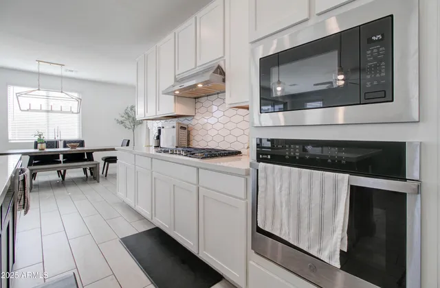 a kitchen with stainless steel appliances kitchen island granite countertop a sink a counter top space and living room view