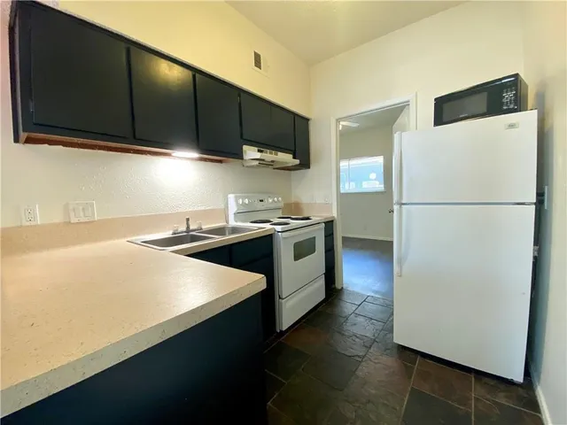 a kitchen with stainless steel appliances a refrigerator a sink a stove a microwave and cabinets
