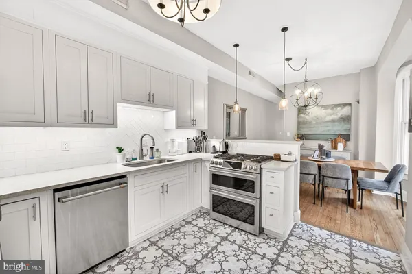 a kitchen with stainless steel appliances a stove a sink and a chandelier