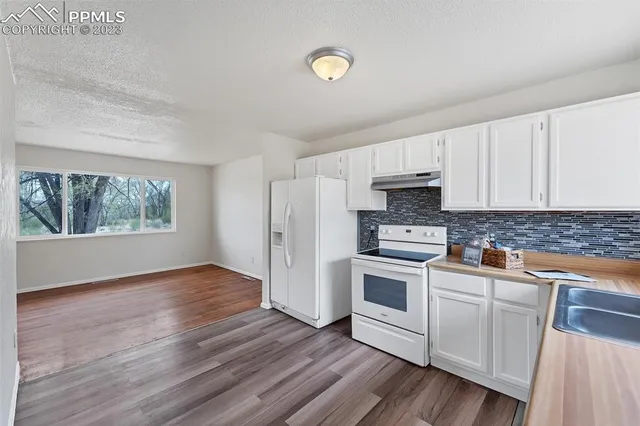 a kitchen with granite countertop white cabinets and white appliances