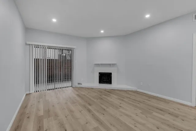 an empty room with wooden floor and fireplace