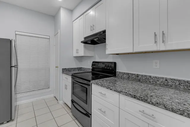 a kitchen with granite countertop white cabinets stainless steel appliances and a sink