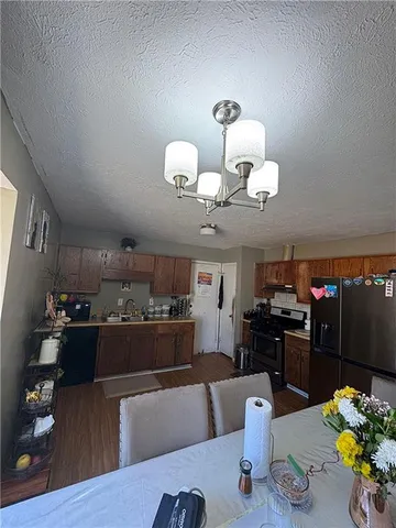 a kitchen with stainless steel appliances granite countertop a refrigerator dining table and chairs