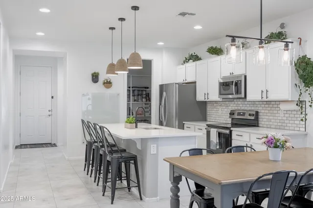 a kitchen with stainless steel appliances granite countertop a dining table chairs stove refrigerator and microwave