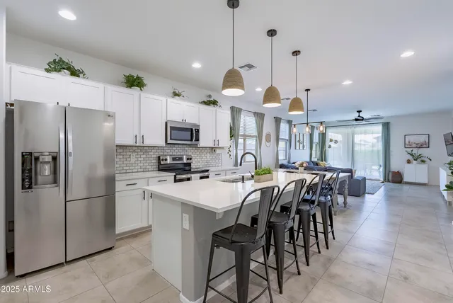 a kitchen with stainless steel appliances a refrigerator a stove a sink a dining table and chairs