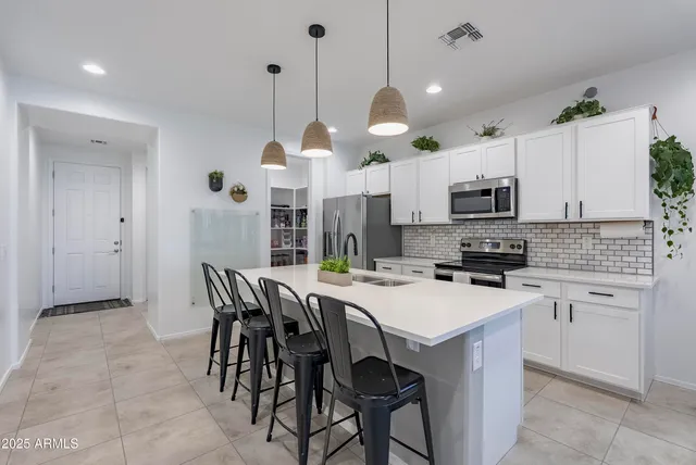 a kitchen with stainless steel appliances a white table chairs and a refrigerator