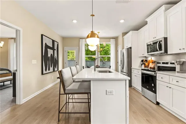 a kitchen with stainless steel appliances granite countertop a stove a sink dishwasher a refrigerator and a dining table with wooden floor