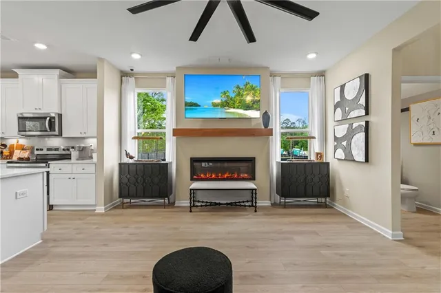 a living room with stainless steel appliances furniture a fireplace and a open kitchen view