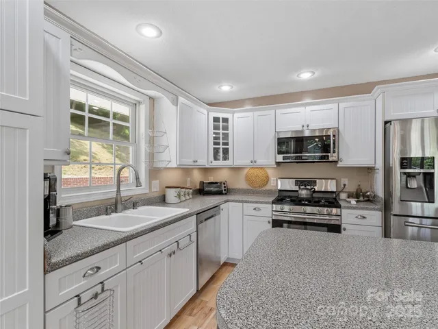 a kitchen with stainless steel appliances granite countertop a stove sink and cabinets
