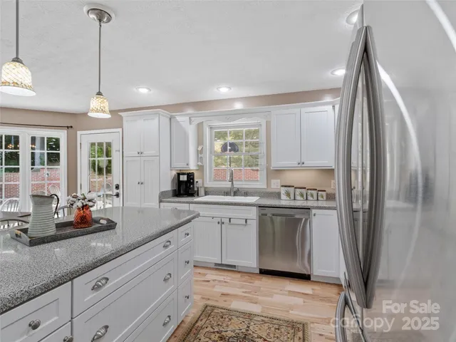 a kitchen with stainless steel appliances granite countertop a refrigerator a sink a stove and white cabinets