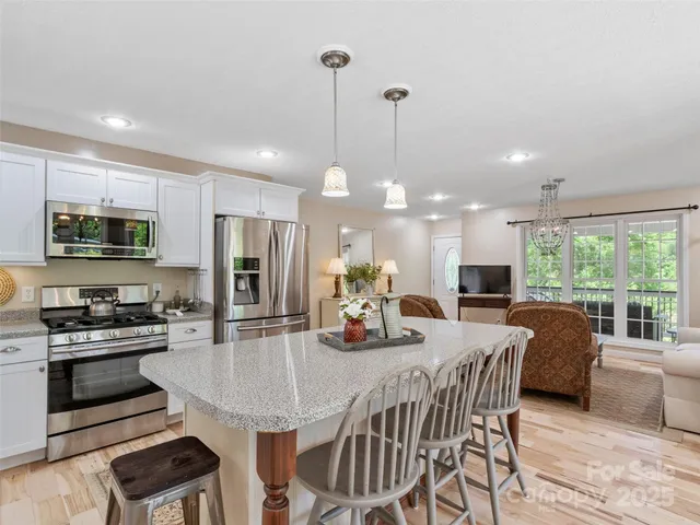 a kitchen with stainless steel appliances granite countertop a stove a refrigerator a kitchen island a dining table and chairs