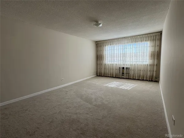 an empty room with a ceiling fan and windows