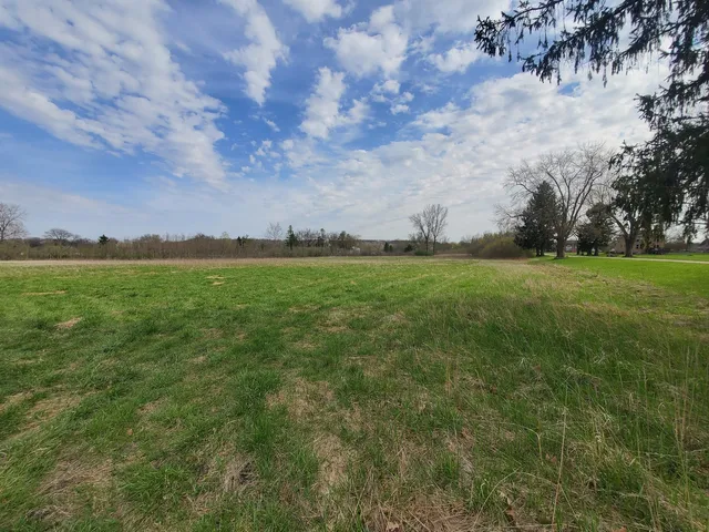 a view of a green field with wooden fence