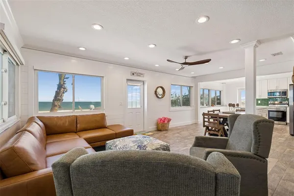 a living room with furniture kitchen view and a large window