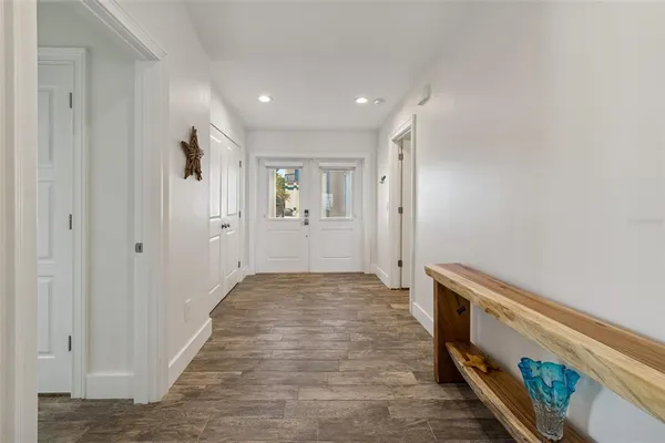 a view of a white house with a swimming pool and lawn chairs under an umbrella