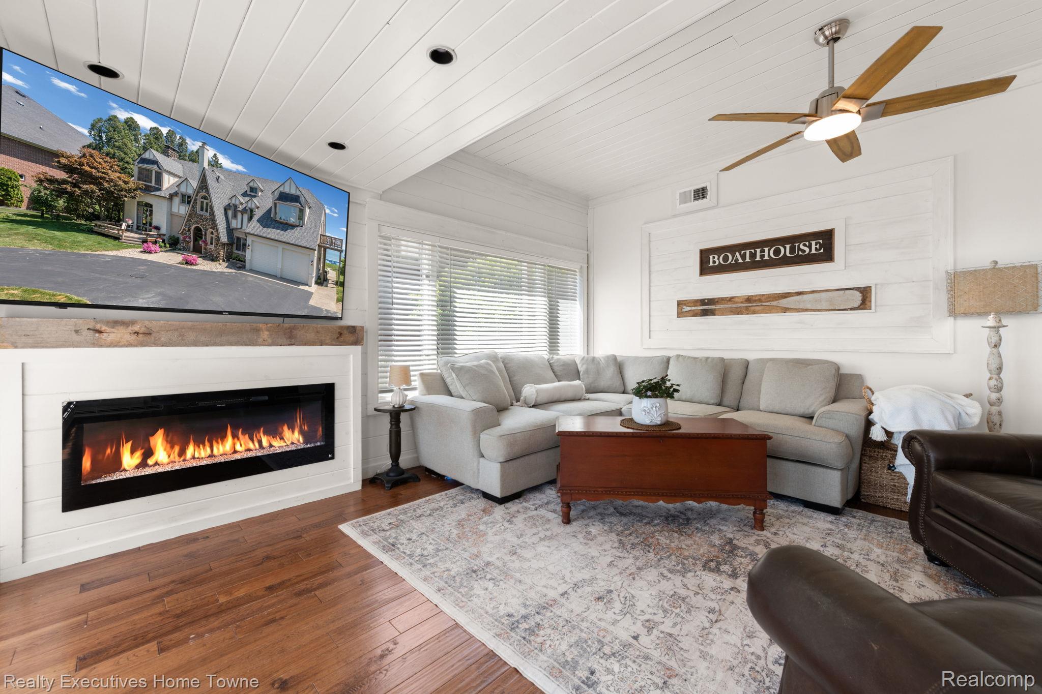 8308 Lakeshore Road Fort Gratiot, MI 48059 - Photo 52 of 79 Living area featuring wood-finish flooring, a contemporary electric fireplace with a wood mantle, and white shiplap walls and ceiling
