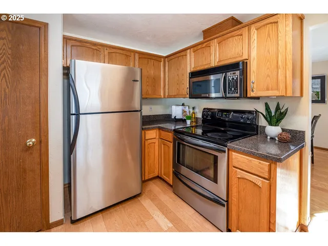 a kitchen with stainless steel appliances granite countertop a refrigerator a stove a sink and a microwave