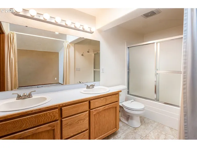 a bathroom with a granite countertop sink toilet a large mirror and shower
